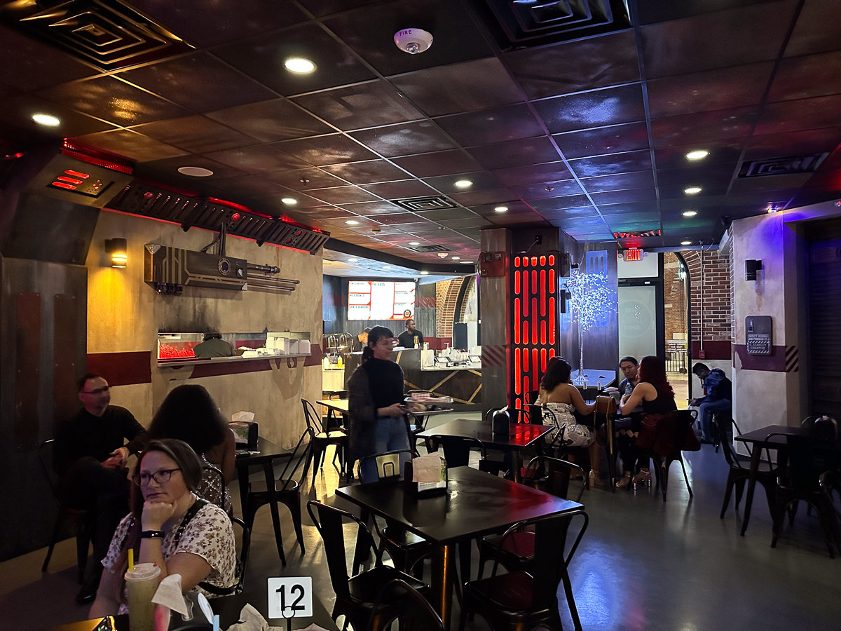 inside restaurant with dark lighting and black tables and chairs